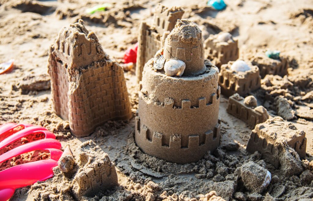Sandcastle structures built on a beach, illustrating the transition from childhood play to the challenges of leadership.